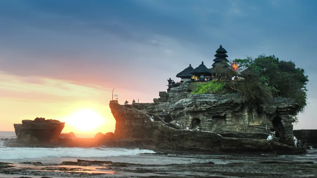 Scenic sunset view of the famous Tanah Lot Temple perched on a rock formation off the coast of Bali, Indonesia.