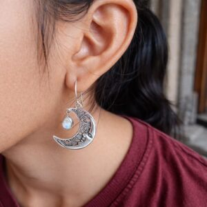 Close-up of Bali silver moon face earrings with detailed carving
