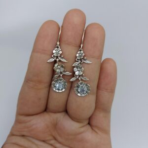 Close-up of floral silver earrings with detailed petals