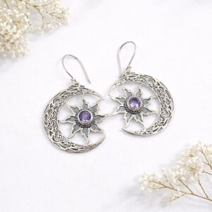 Close-up of boho silver earrings with sun and moon symbols
