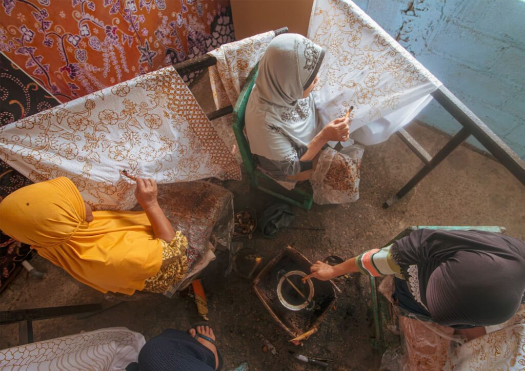Indonesian batik artisan creating handmade fabric using traditional technique